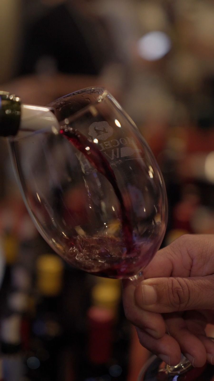 Taça de tinto em primeiro plano, com o salão do Mocellin ao fundo